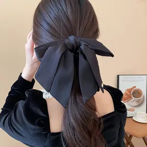 Detailed view of a large black satin bow hair claw clip worn on long hair