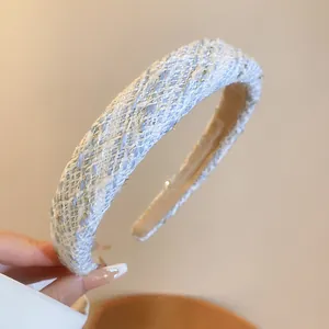 Close-up detail of light blue tweed headband with elegant gold metallic thread accents.