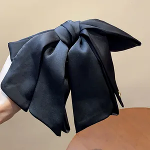 Macro view of the elegant black fabric bow hair claw clip with satin-like texture