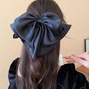 Close-up showing the elegant satin texture of a large black bow hair claw clip accessory.