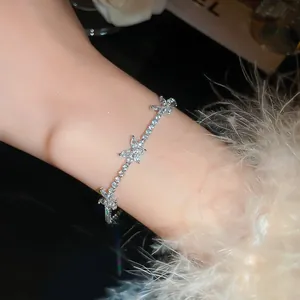 Élégant bracelet papillon en zircon porté au poignet avec détail de manche duveteuse.