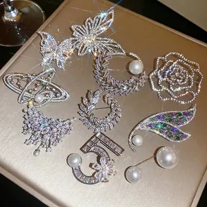 Elegante collezione di spille con strass a farfalla e perle per abbigliamento di lusso.