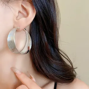 Primo piano di grandi orecchini a cerchio in argento testurizzato indossati da modella