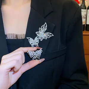 Vista dettagliata di due spille a farfalla scintillanti con accenti di perle su un blazer nero.