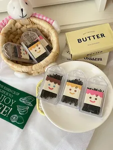 Close-up view of black bobby pins in cute cartoon-themed portable cases on a plate.