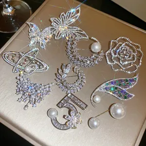 Dettaglio di spille di lusso con strass e perle a forma di farfalla e saturno