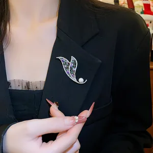 Dettaglio di una spilla a farfalla con perle e strass su un blazer nero da donna.