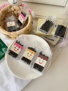 Detailed view of black bobby pins in cute cartoon storage cases on a white plate