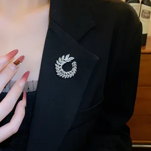 Elegante spilla a ghirlanda di foglie d'argento con strass luccicanti su blazer nero