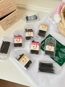Close-up detail of black bobby pins in transparent portable cases with cute cartoon inserts.