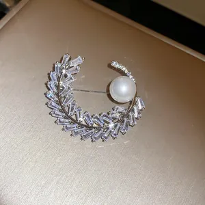Primo piano dettagliato di una spilla a mezzaluna in zircone con una lucente perla bianca