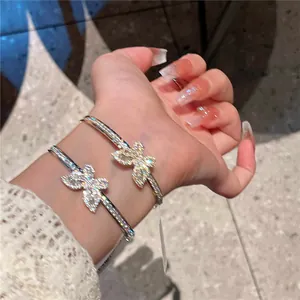 Detailed macro view of elegant butterfly open bangles with sparkling zircons on model's wrist