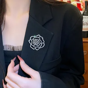 Primo piano di una spilla a forma di camelia scintillante su un blazer nero
