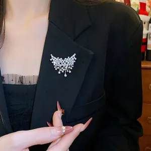 Squisita spilla a farfalla con strass scintillanti e perle sul bavero di un blazer.