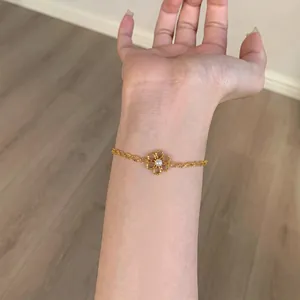 Gros plan d'un bracelet fleuri doré minimaliste avec perle sur le poignet