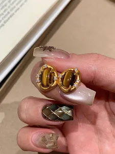 Detailed view of gold-plated oval stud earrings with tiger eye stone and zircons.