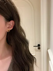 Elegant oval gold-plated stud earrings with brown stone worn by a model in a close-up.