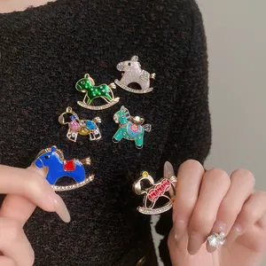 Macro view of colorful enamel rocking horse brooches with rhinestone details on a sweater