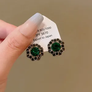 Primo piano di eleganti orecchini a lobo a fiore con una grande gemma verde