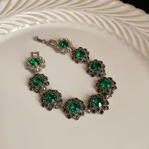 Vista dettagliata di un bracciale vintage con fiori verde smeraldo su un piatto bianco
