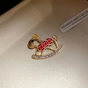 Close-up of a vintage rocking horse brooch with red enamel and clear rhinestones