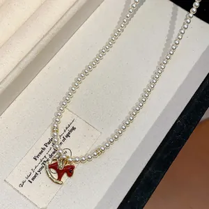 Close-up detail of a French style pearl necklace featuring a red enamel rocking horse pendant
