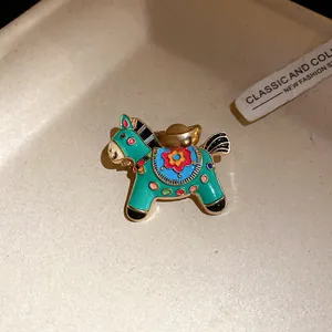 Close-up of a vintage enamel horse brooch with colorful patterns and gold-tone details