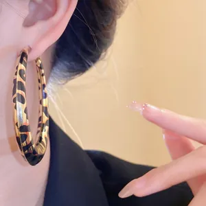 Vista detallada de pendientes de aro con estampado de leopardo en la oreja de una modelo
