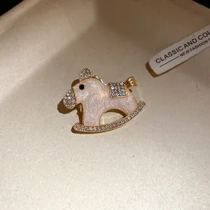 Close-up of elegant pink enamel rocking horse brooch with sparkling rhinestones