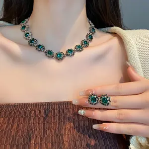 Primo piano di collana a fiori vintage e orecchini di cristallo verde su modella.