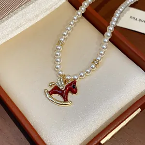Close-up of a French style pearl necklace with a red rocking horse pendant in a box