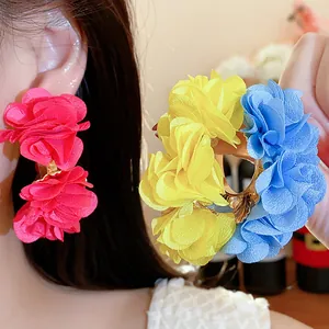 Detail shot of vibrant chiffon flower C-shaped earrings in pink, yellow and blue.