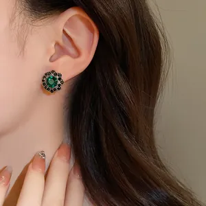 Primo piano di orecchini a lobo vintage a fiore verde smeraldo indossati da una modella asiatica