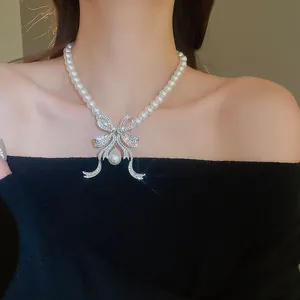 Collier de perles élégant avec un nœud en diamant scintillant et un pendentif perle.