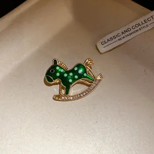 Close-up of vintage green enamel rocking horse brooch with sparkling rhinestones