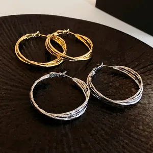 Detailed macro view of gold and silver twisted crossover geometric hoop earrings set
