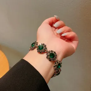Primo piano di un elegante bracciale a fiori vintage con cristalli verdi scintillanti sul polso