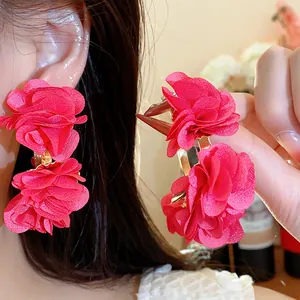 Detailed shot of elegant red chiffon fabric flower C-shaped hoop earrings on model.