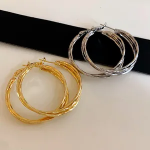 Detail view of gold and silver twisted geometric hoop earrings on black ribbon backdrop