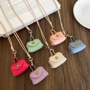 Set of colorful mini leather bag necklaces on wooden surface with decorative props
