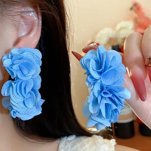 Close-up of elegant blue chiffon flower C-shape hoop earrings with fabric texture.