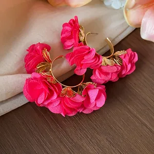 Detailed close-up of bright pink chiffon flower hoop earrings with golden leaf accents