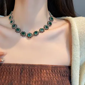 Dettaglio di una collana vintage con fiori verde smeraldo sulla clavicola della modella