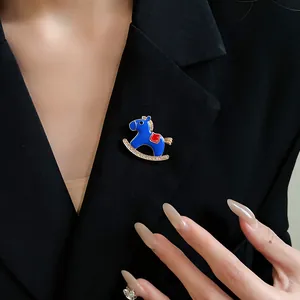 Detailed shot of a blue enamel rocking horse brooch with sparkling crystals on a black blazer.