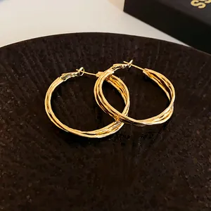 Detailed close-up showing the intricate twisted texture of these golden geometric hoop earrings