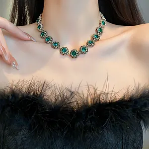 Dettaglio macro della collana floreale vintage con strass verde smeraldo su una modella