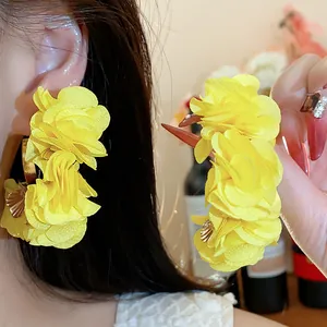 Detail showing vibrant yellow chiffon flower C-shaped earrings with soft texture.