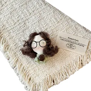 Handmade brunette girl doll brooch with glasses on a textured woven background