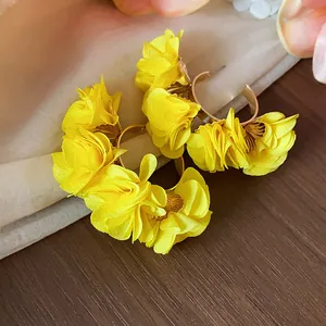 Detail shot of vibrant yellow chiffon flower hoop earrings with high-end texture.