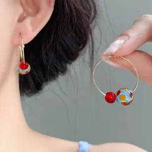 Detailed view of handmade colorful resin bead hoop earrings worn by a female model